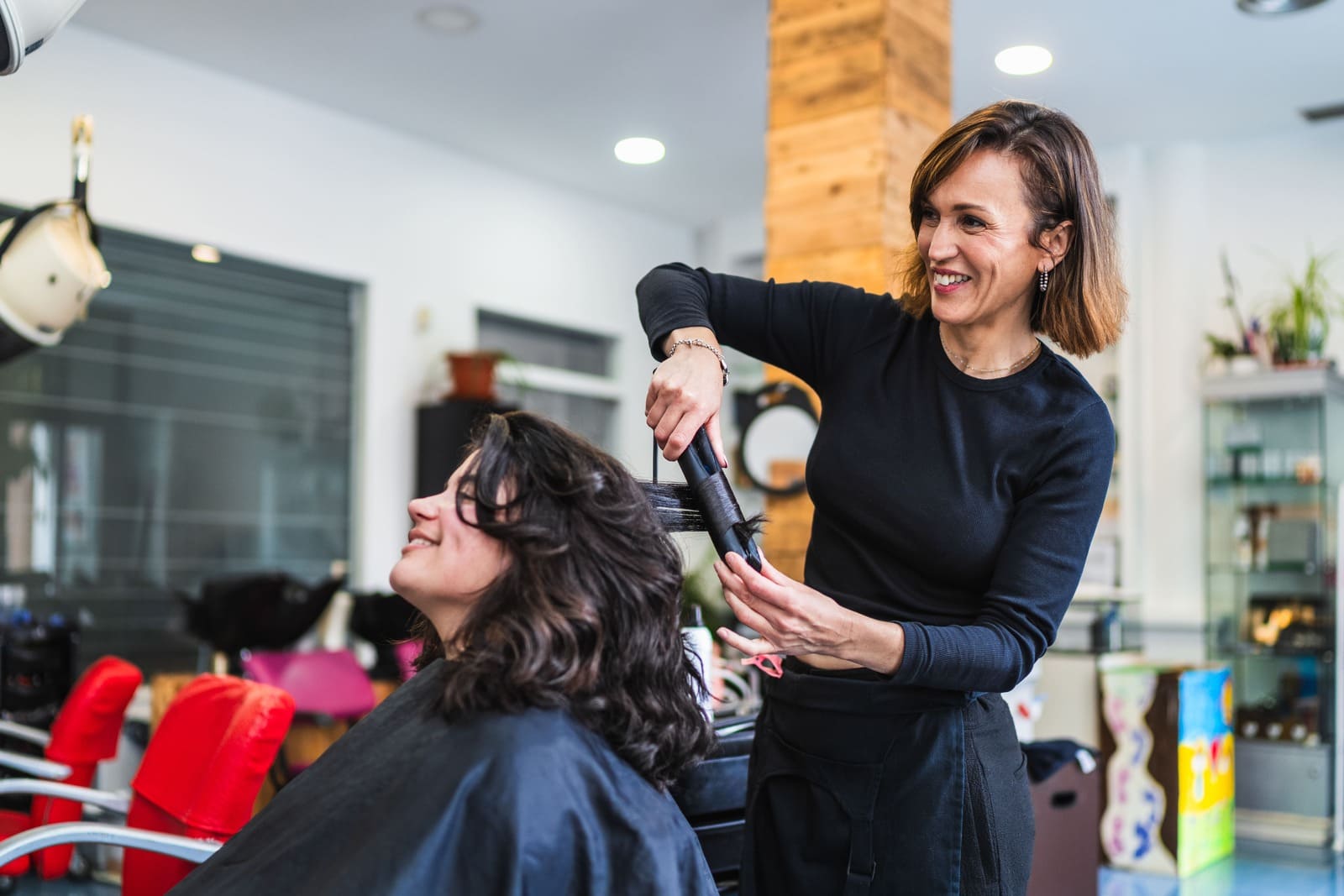 Frizerka radi frizuru klijentkinji u salonu
